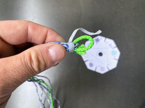 <H3><b>Entferne das dünne Papierband bei der Schlaufe. Achte darauf, dass die Schnüre zusammen bleiben.</b>